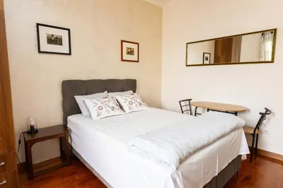 a bedroom with a white bed with a table and a mirror at Ugi house - City Center in Belgrade