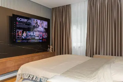 a bedroom with a bed and a flat screen tv at Royalux Kennedy Residences in Tošin Bunar