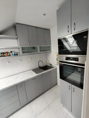 a white kitchen with a sink and a stove at Privatna soba Marijana-Olja in Surčin