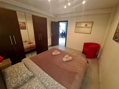 a bedroom with a large bed and a red chair at Fantastic Belgrade Nights in Belgrade