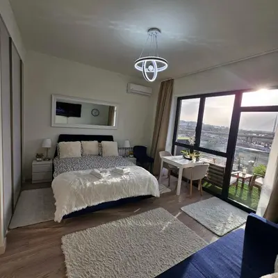 a bedroom with a bed and a table with a view at Belgrade Waterfront Galerija Apartment in Sajmište