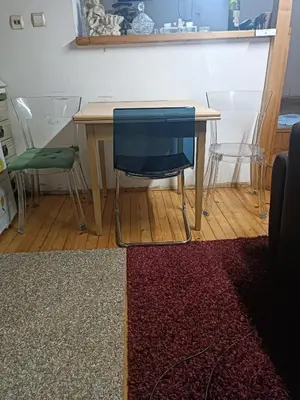 a table with a blue chair and a table with a rug at Maravilja 23 in Filmski Grad