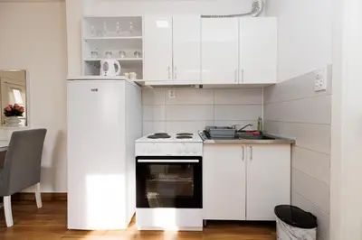 a kitchen with white cabinets and an oven at Apartman Aki in Bele Vode