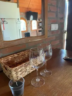 two wine glasses on a wooden table with a mirror at River House in Belgrade