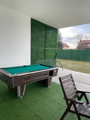 a pool table and a chair on a lawn at Kuca sa bazenom Oazis in Pećinci