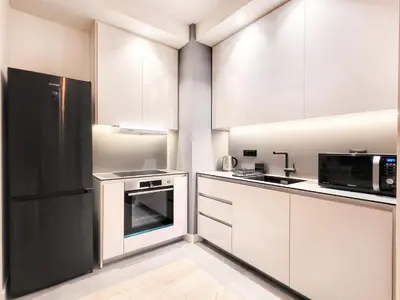 a kitchen with white cabinets and a black refrigerator at Panoramic View Lux Apartment BW in Sajmište