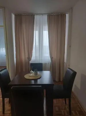 a dining room with a table and chairs and a window at Toni apartments in Voždovac