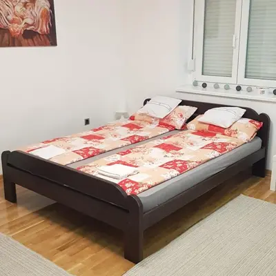 a bed in a room with a bed frame with pillows at Apartman Vojvoda in Sajmište
