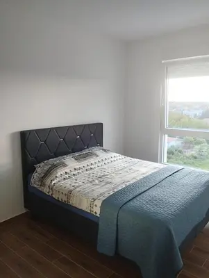 a bed in a white room with a window at Amare in Inđija