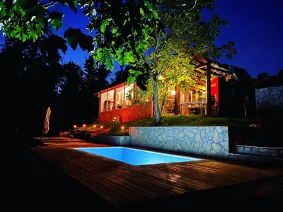a swimming pool in front of a house at night at Šumska Vila Lipovica in Barajevo