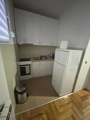 a small kitchen with white cabinets and a refrigerator at Altina Gottfried Studio in Novi Grad