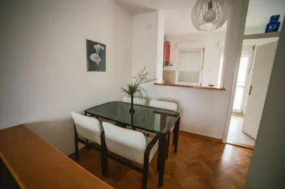 a dining room with a glass table and white chairs at Viktorija Apartment in Belgrade