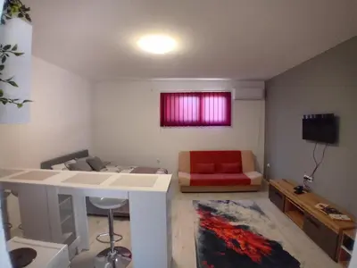 a living room with a couch and a red chair at AlejaPark Inđija in Železnicka Stanica Inđija Selo