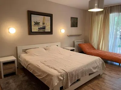 a bedroom with a bed and a chair and a window at Malvex in Belgrade