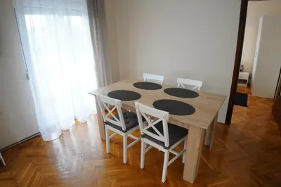 a dining room table with four chairs and a table at Apartmani Kula in Novi Banovci