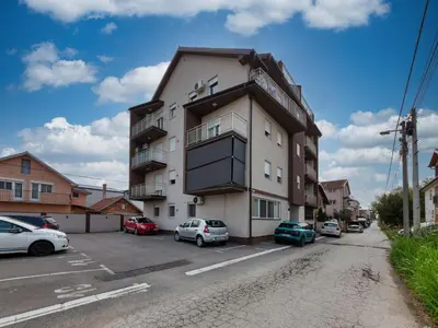 a building with cars parked in a parking lot at Apartment SIX - free parking in Belgrade