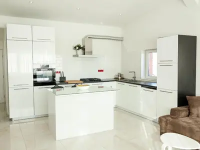 a white kitchen with white cabinets and a couch at Golden Gate 21 in Ruma