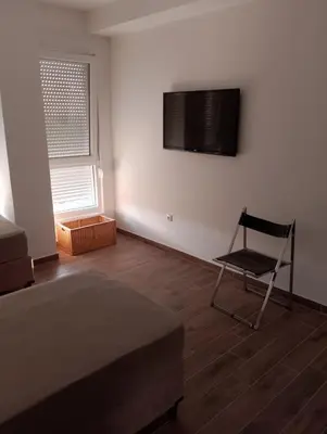 a bedroom with a bed and a chair and a television on the wall at Amare2 in Inđija