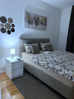 a bedroom with a bed and a night stand with a lamp at PLEASURE LUX Bg in Belgrade