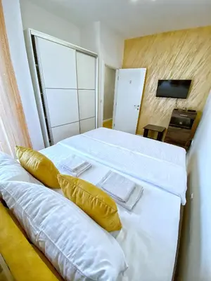 a bedroom with a bed with white sheets and yellow pillows at PLEASURE LUX Bg in Belgrade