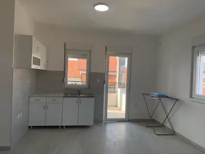a kitchen with white cabinets and a table in it at Appartement 2 chambres et 1 salon près de l'aéroport de Belgrade in Belgrade