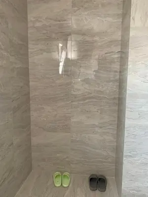 two pairs of green shoes on the floor of a shower at Appartement 2 chambres et 1 salon près de l'aéroport de Belgrade in Belgrade