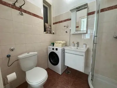 a bathroom with a toilet a sink and a washing machine at Eight Apartment in Belgrade