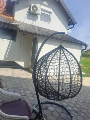 a bird cage on a chair in front of a house at Apartmani Petrušić