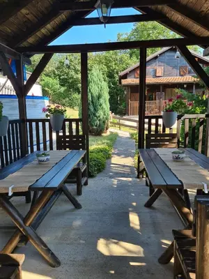 a group of wooden picnic tables under a pavilion at Kosmajski vajati Petra in Nemenikuće