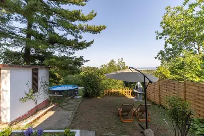 a backyard with chairs and an umbrella and a fence at Kućica na brdu-Zaklopača in Zaklopača