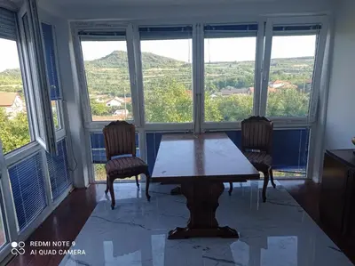 a table and two chairs in a room with windows at Sunny Villa in Belgrade