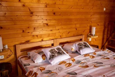 a bedroom with a bed with a wooden wall at etno brvnara sa bazenom in Železnička Stanica Karlovački Vinogradi