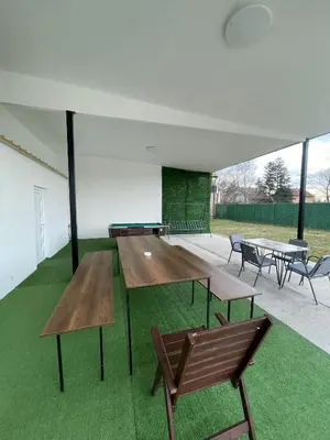 a group of tables and benches in a room with grass at Apartman na dan Pecinci in Pećinci