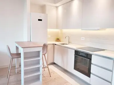 a white kitchen with a table and a refrigerator at Simphonia Lux Apartments BW in Belgrade