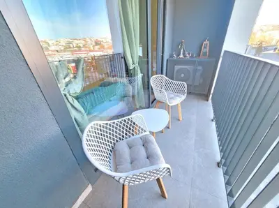a balcony with two chairs and a table and a window at Simphonia Lux Apartments BW in Belgrade