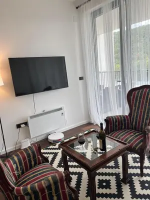 a living room with two chairs and a table and a tv at Cozy apartment Kosmaj Residence in Rogača