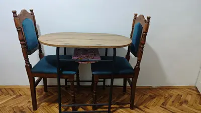 a wooden table and two chairs with blue seats at hometown in Pančevo