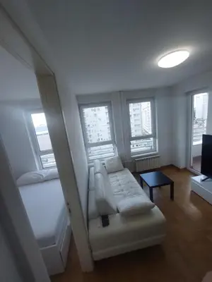 a living room with a couch and a bed and windows at DELTA CITY apartments in Novi Beograd