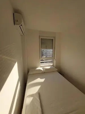 a bed in a small room with a window at DELTA CITY apartments in Novi Beograd