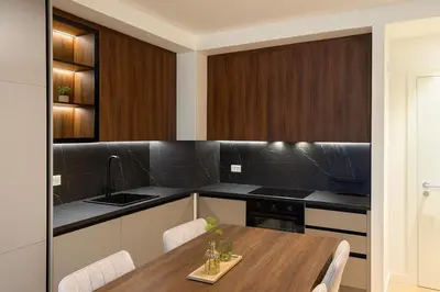 a kitchen with a wooden table and black counter tops at Belgrade Waterfront Premium LuX Apartment in Sajmište