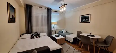 a hotel room with two beds and a table and chairs at Retiro Apartman in Belgrade