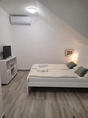 a white bedroom with a bed and a tv at Beosan in Železnička Stanica Zemunsko Polje