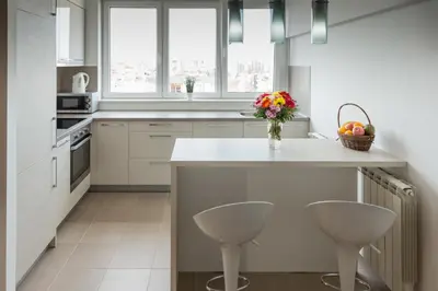 a kitchen with a counter with two stools and a vase of flowers at Apartment Admiral in Belgrade