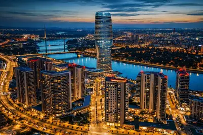 a city skyline at night with a tall skyscraper at Metropoliten Modern Apartment in Belgrade