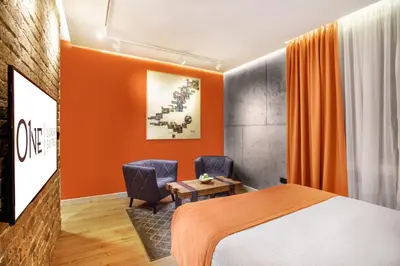 a hotel room with a bed and two chairs at One Luxury Suites in Belgrade