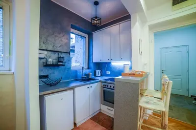 a kitchen with white cabinets and a table and a chair at Panorama Central Apartments in Belgrade