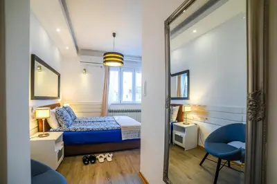 a bedroom with a bed and a chair and a mirror at Panorama Central Apartments in Belgrade