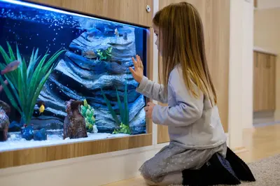 a little girl sitting in front of a fish tank at Airport Hotel Garni in Belgrade