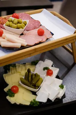 a tray of cheese and meats and vegetables on a table at Airport Hotel Garni in Belgrade