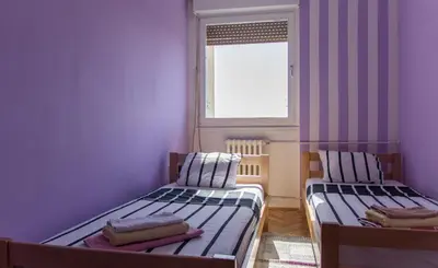two beds in a small room with a window at Sunny Apartment in Belgrade